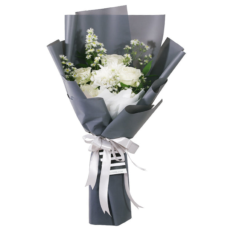 An elegant bouquet featuring a monochromatic white and grey theme. The arrangement is composed of classic white roses, asters, and peacock, delicate baby's breath, and other smaller white filler flowers. The flowers are wrapped in a clean, white inner layer and a sophisticated grey outer layer. The bouquet is tied with a double white ribbon—and a small tag. The minimalist style makes it a thoughtful gift for any occasion.